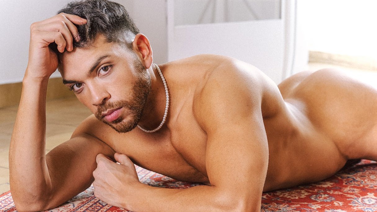 Maxi reclining on a red patterned rug, wearing a pearl necklace - DNA #279