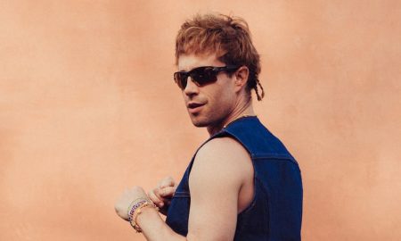 Geordie Kieffer in a denim vest and sunglasses against a terracotta wall