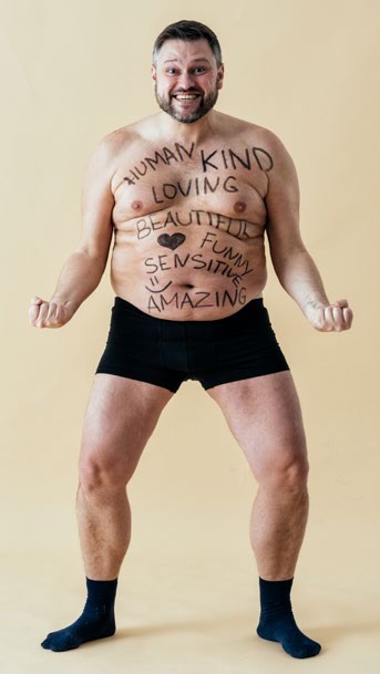 Man with positive words written on his body including Human, Kind, Loving, Beautiful, Amazing
