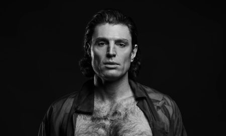 Reuben Kaye in a black and white studio portrait, open shirt, intense gaze