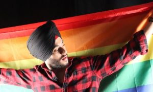 Inderjit holding a Pride flag while wearing his turban in Toronto