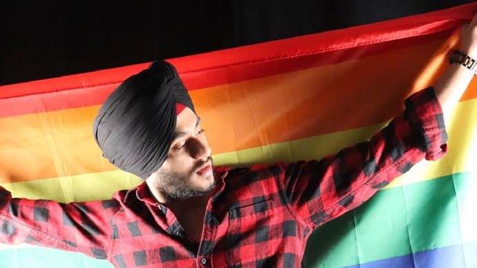 Inderjit holding a Pride flag while wearing his turban in Toronto