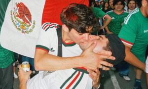 Issac Flores kisses his boyfriend Edson Gonzalez in front of a Mexican flag at a World Cup watch party in Mexico City
